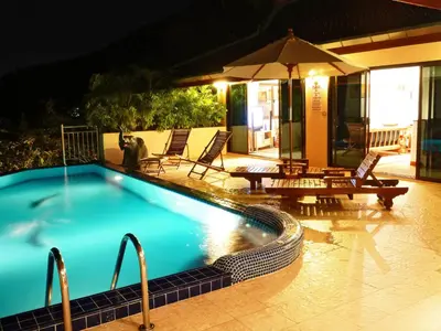 a swimming pool at night with chairs and an umbrella at Villa Malee , Sea View Infinity Pool, Staff, Chef in Kata Beach