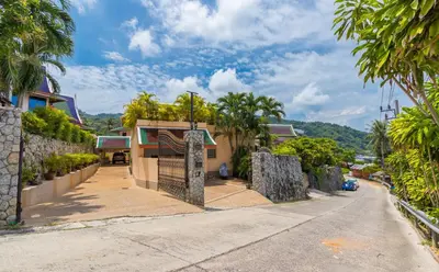 a street in front of a house with palm trees at Villa Malee , Sea View Infinity Pool, Staff, Chef in Kata Beach