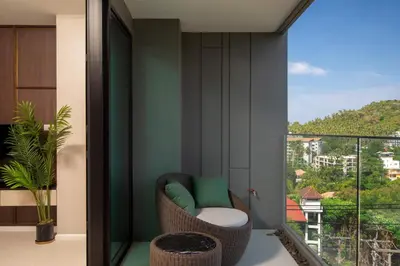 a room with a balcony with a chair and a window at 3bdr SeaView Apartment in Surin Beach by Capital Pro in Phuket Town