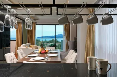 a dining room with a table and chairs and a living room at 3 bdr SeaView Apartment walking to Surin Beach by CapitalPro in Phuket Town