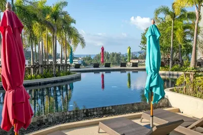 a pool with two umbrellas in a resort at Mountain view Apartment Surin Beach 716 by CapitalPro in Phuket Town