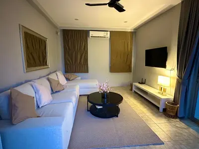 a living room with a white couch and a tv at Peaceful Retreat Villa by Nai Thon beach in Phuket Town