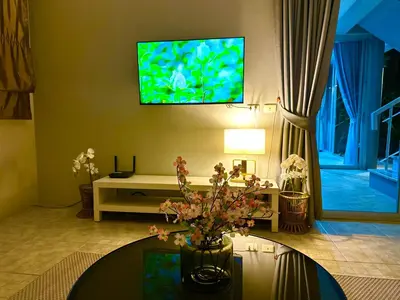 a living room with a table and a tv on the wall at Peaceful Retreat Villa by Nai Thon beach in Phuket Town