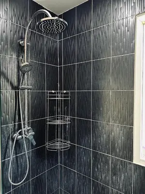 a black tiled bathroom with a shower with two baskets at Peaceful Retreat Villa by Nai Thon beach in Phuket Town
