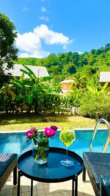 a table with a drink and some flowers on it at Peaceful Retreat Villa by Nai Thon beach in Phuket Town