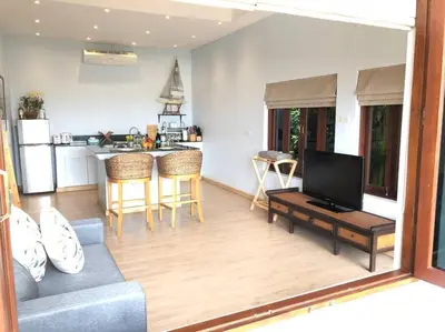a living room with a couch and a table and a kitchen at 1 bedroom Villa on Ao Yon beach with sea views in Phuket Town