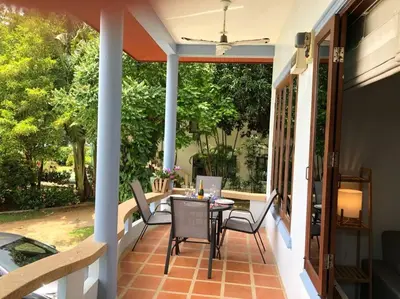 a patio with a table and chairs on a porch at 1 bedroom Villa on Ao Yon beach with sea views in Phuket Town