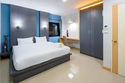 a bedroom with a bed and a desk in a room at Chalong - Studio Service Apartment - Phoomjai in Ban Klang