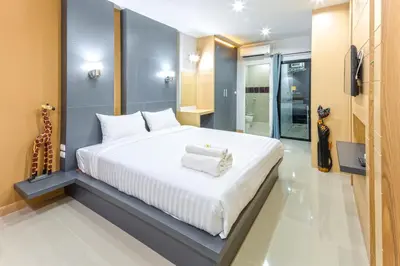 a bedroom with a large white bed and a bathroom at Chalong - Studio Service Apartment - Phoomjai in Ban Klang