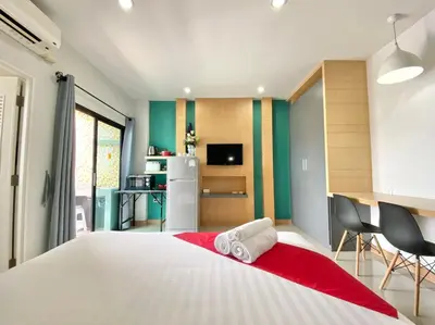 a bedroom with a large white bed with a red blanket at Chalong - Studio Service Apartment - Phoomjai in Ban Klang