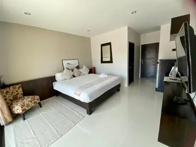 a bedroom with a bed and a chair in it at SD Residence I Naiyang Beach I HKT Airport in Nai Yang Beach