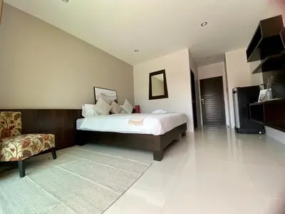 a large bedroom with a bed and a chair at SD Residence I Naiyang Beach I HKT Airport in Nai Yang Beach
