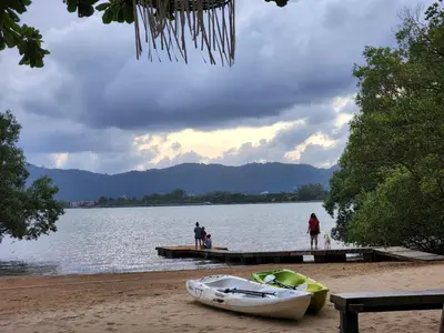 a boat on the shore of a lake with people on a dock at Baan Panwa Resort in Panwa Beach