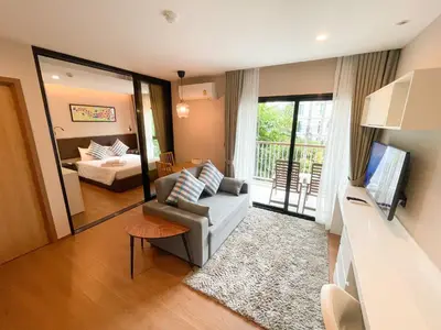 a living room with a couch and a bed and a mirror at The Title V Condos by Gregory in Rawai Beach