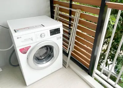 a white washing machine sitting next to a fence at The Title V Condos by Gregory in Rawai Beach