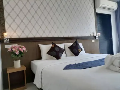 a bedroom with two beds and a vase of flowers at NJ PATONG HOTEL in Patong Beach