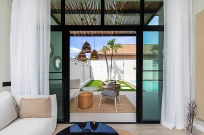a living room with a view of a patio at Onyx Villas by TropicLook in Nai Harn Beach