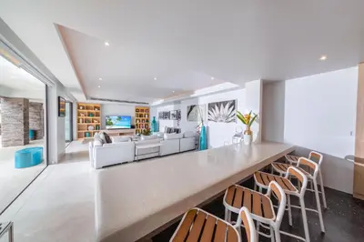 a large living room with a long counter with chairs at Villa La Prana in Phuket Town