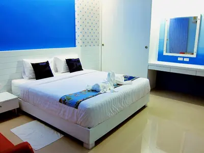 a bedroom with a large white bed with blue walls at Forest Bungalows & Mama's Restaurant in Chalong