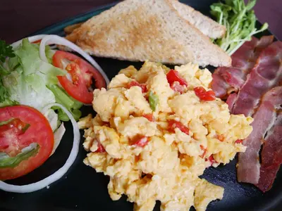 a plate of food with scrambled eggs and a salad at Forest Bungalows & Mama's Restaurant in Chalong