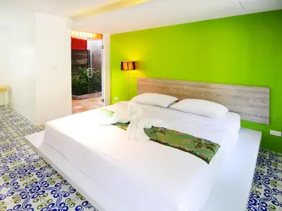 a bedroom with a white bed with a green wall at Forest Bungalows & Mama's Restaurant in Chalong