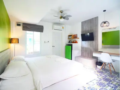 a white bedroom with a bed and a desk at Forest Bungalows & Mama's Restaurant in Chalong