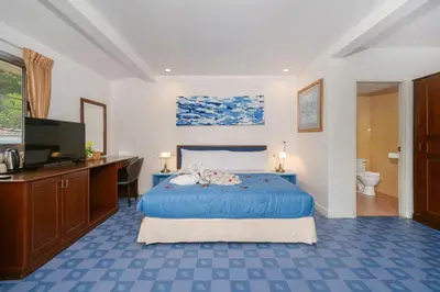 a bedroom with a blue bed and a television at Oceanview Bungalows by EAT in Karon Beach