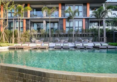 a swimming pool with lounge chairs in front of a building at Уютные апартаменты в Mide Grant in Phuket Town