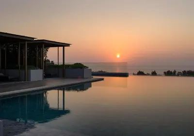 a sunset over a swimming pool at a house at Уютные апартаменты в Mide Grant in Phuket Town