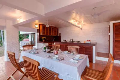 a dining room with a table and a kitchen at Baan Khunying - Secluded Phuket Beachfront Villa in Rawai Beach