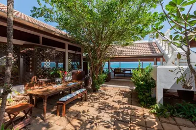a patio with a table and benches in front of a house at Baan Khunying - Secluded Phuket Beachfront Villa in Rawai Beach