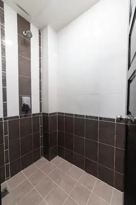 a bathroom with a shower with brown and white tiles at GP House Phuket Patong Beach in Patong Beach