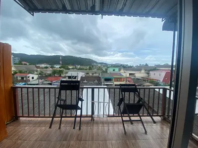 two chairs on a balcony with a view of a city at Sleep Easy in Kata Beach