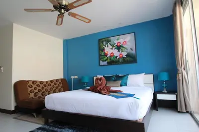 a bedroom with a bed with a blue wall at Sleep Easy in Kata Beach