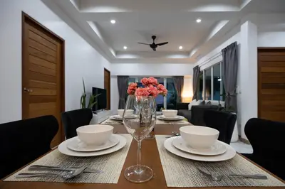 a dining room table with a vase of flowers on it at Private Pool Villa Rawai Beach in Rawai Beach