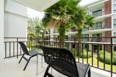 a balcony with chairs and a table and a building at New Apartment TTL B209 in New Rawai Beach Residence with Tropical Pools in Rawai Beach