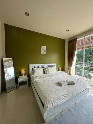 a bedroom with a large bed with a green wall at TIL DAWN Phuket in Karon Beach