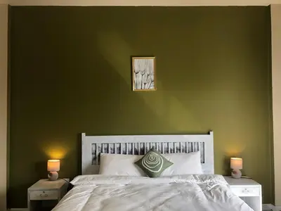 a bedroom with a green wall with a bed and two lamps at TIL DAWN Phuket in Karon Beach