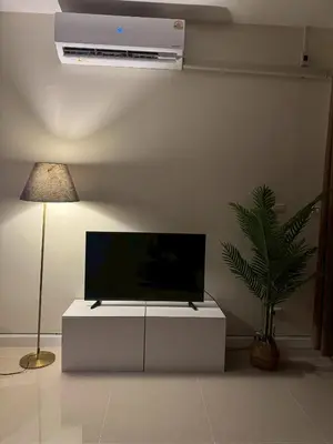 a living room with a flat screen tv on a white cabinet at TIL DAWN Phuket in Karon Beach