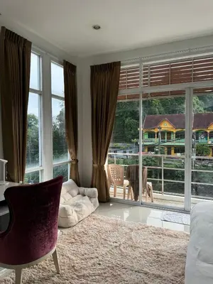 a living room with a couch and a large window at TIL DAWN Phuket in Karon Beach