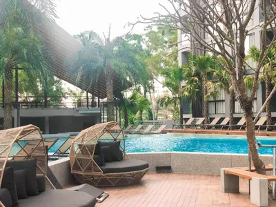 a swimming pool with two lounge chairs next to a building at Kamala Beach D76 Exclusive Junior Suite in Kamala Beach
