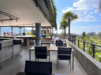 a restaurant with tables and chairs on a balcony at Kamala Beach D76 Exclusive Junior Suite in Kamala Beach