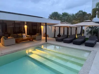 a swimming pool with chairs and umbrellas next to a house at Beautiful private 4 bedroom villa with pool and gym in Rawai Beach