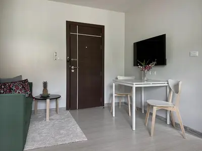 a living room with a table and a television at Great Hill Cozy Stay Pool Gym Naiyang in Phuket Town