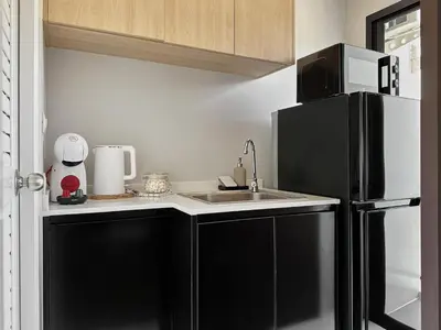 a kitchen with a black refrigerator and a sink at Great Hill Cozy Stay Pool Gym Naiyang in Phuket Town