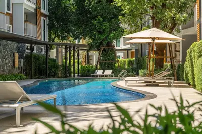 a pool with chairs and an umbrella next to a building at Title V Sunny Holiday Pool View Gym Hammam in Rawai Beach