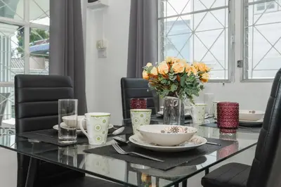 a dining room table with a vase of flowers on it at Karon Beach Holiday Home 1 in Karon Beach