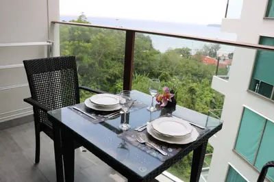 a table with plates and glasses on a balcony at Oceana Resort Kamala Ocean View 5th floor in Kamala Beach