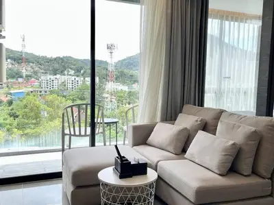 a living room with a couch and a large window at Kamala Beach P55 Exclusive Junior Suite in Kamala Beach