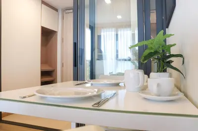 a table with plates and cups and a plant on it at Sky Park Laguna 1 bedroom Golf View in Bang Tao Beach
